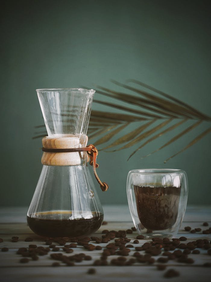 A minimalist coffee setup featuring a Chemex and glass with roasted coffee beans. Perfect for a cozy coffee break.
